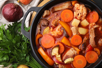 Tasty homemade stew with vegetables on grey wooden table, flat lay