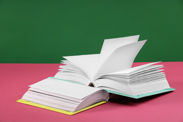 Wall Mural - Colorful books on pink table against green background