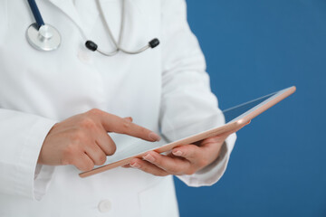 Doctor with tablet on blue background, closeup view