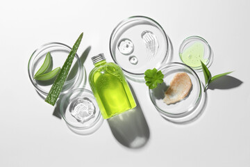 Wall Mural - Petri dishes with different cosmetic products and aloe vera leaves on white background, flat lay