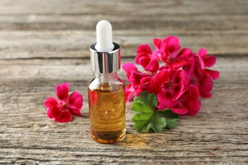 Wall Mural - Bottle of geranium essential oil and beautiful flowers on wooden table