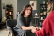 © Mediaphotos - Female therapist sitting opposite to client, holding hands in supportive gesture during counseling session in well-decorated office environment
