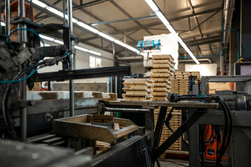 Worker handling stacks of wooden planks in a woodworking factory, preparing materials for further processing under industrial lighting