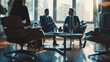 © elena_hramowa - Blurred image of business professionals in suits having a meeting in a modern office lounge with large windows and cityscape view.