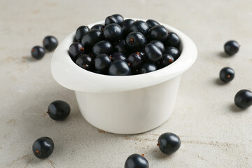 Wall Mural - Ripe black currants in bowl on light table, closeup