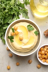 Poster - Delicious hummus with olive oil, chickpeas and parsley on light textured table, flat lay