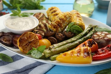 Wall Mural - Delicious grilled vegetables with sauce on light blue table, closeup