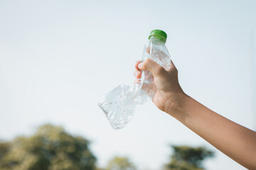 Wall Mural - Recyclable plastic bottle held in hand up on sky background. Hand holding plastic waste for recycle reduce and reuse concept to promote clean environment with effective recycling management. Gyre