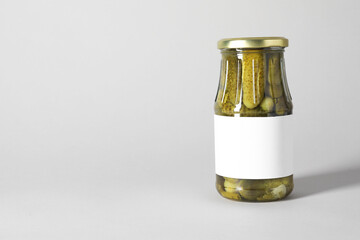 Wall Mural - Pickled cucumbers in jar on light background. Space for text