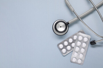 Wall Mural - Antibiotic pills in blisters and stethoscope on gray background, flat lay. Space for text