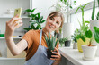 © Maria Vitkovska - Woman taking selfie with plants using smartphone at home