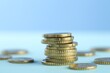 © New Africa - Stack of euro coins on light blue background, closeup