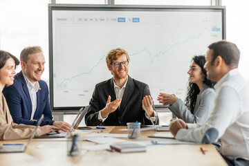 Aufkleber - A group of diverse business professionals are gathered around a conference table in a modern office setting. They are looking at large screen displaying a growth chart, engaging in lively discussion