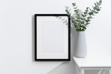 Wall Mural - Vertical black artwork frame mockup on white wall with fresh eucalyptus bouquet in big grey vase, blank mock up with copy space