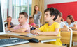 © JackF - Diligent elementary school student preteen boy studying with classmates, making notes of teacher lecture