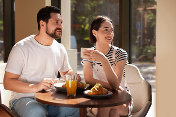 Wall Mural - Happy couple having tasty breakfast in cafe