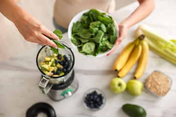 Poster - Woman making delicious smoothie with blender at white marble table in kitchen, above view