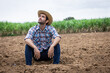 © kamonrat - Contemplative Farmer Sitting on Barren Land, Reflecting on the Challenges of Agriculture, Drought, and the Unpredictability of Nature in a Rural Farm Setting