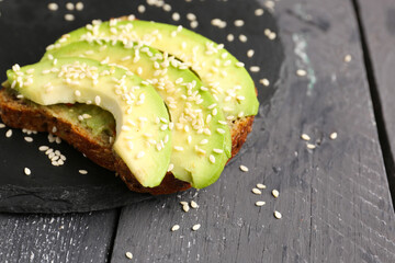 Sticker - Slate board of tasty avocado toast on dark wooden background, closeup