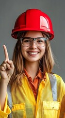 Wall Mural - young woman in construction uniform and red safety helmet smiling and pointing with finger