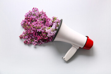 Wall Mural - Creative composition with megaphone and beautiful lilac flowers on light background