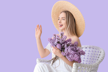 Poster - Young woman with lilac flowers in armchair on color background