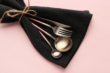 Wall Mural - Stylish cutlery in black napkin on pink background