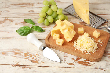 Board with tasty Swiss cheese on light wooden background