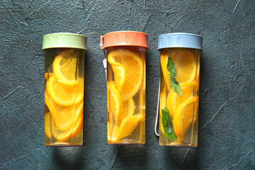 Sticker - Sports bottles of infused water with orange slices on blue background