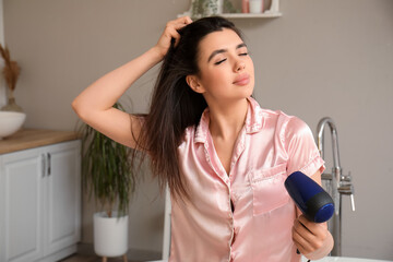 Wall Mural - Pretty young woman with hair dryer in bathroom