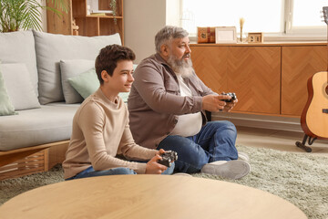 Wall Mural - Happy grandfather with his cute grandson playing video games at home