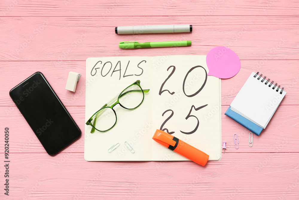 Notebook with to do list and mobile phone on pink wooden background. New year goals concept