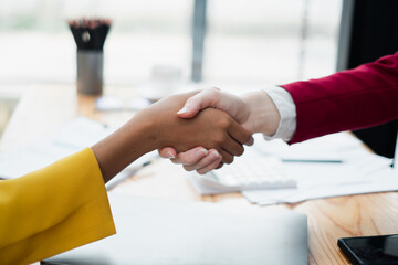 Close-up of a handshake between two professionals in a modern office, symbolizing partnership and agreement.