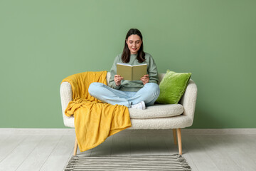 Sticker - Young woman reading book on sofa in green living room