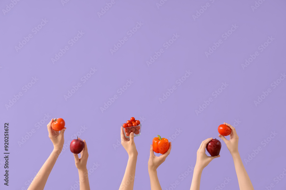 Hands with fresh tomatoes, apples and bell peppers on lilac background