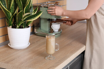 Wall Mural - Young woman making iced latte in kitchen