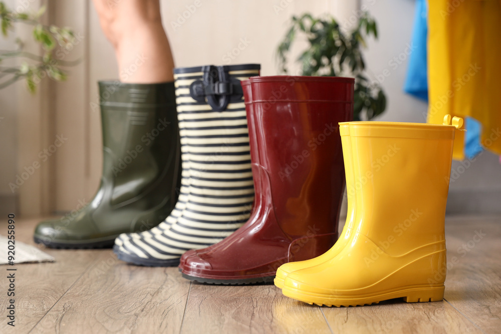 Beautiful young woman with different rubber boots in hallway, closeup