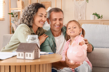 Wall Mural - Happy family with piggy bank at home