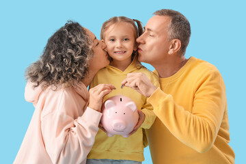 Poster - Happy family with piggy bank and coins on blue background