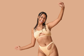 Sticker - Beautiful young African-American woman in stylish swimsuit on brown background