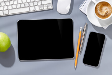 Blank screen smartphone and tablet on a desk