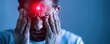 © Mnt - A man experiencing severe headache, holding his head in pain, illuminated by a red light in a dimly lit environment.