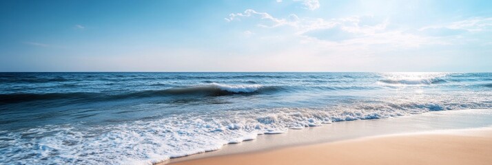 Wall Mural - Tranquil blue ocean with white capped waves lapping on a sandy beach under a bright, blue sky with white clouds.