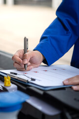 Wall Mural - action of a mechanic worker in blue uniform is using a pen to checking on safety checklist form to v
