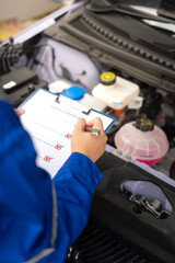 Wall Mural - action of a mechanic worker in blue uniform is using a pen to checking on safety checklist form to v