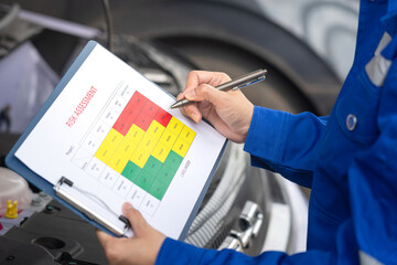 Wall Mural - An engineer is using a pen to checking on the safety risk assessment with color matrix form to evaluate the risk level. Industrial ot business working scene, close-up and selective focus.