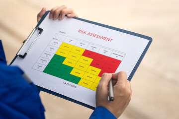 Wall Mural - an engineer is using a pen to checking on the safety risk assessment with color matrix form to evalu