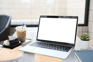 Wall Mural - Laptop, coffee and chocolate cake on glass table in modern cafe