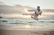 © peopleimages.com - Karate, man and jump kick at beach for exercise, body health and taekwondo outdoor. Fighter, flying and practice martial arts at ocean for fitness, workout and energy with power at sunset in summer