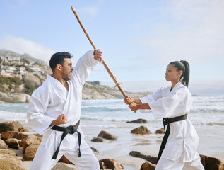 Poster - Martial arts, practice sword and people training at beach for fitness, fight and block attack. Karate, man and woman with wood shinai for exercise with teacher and samurai at ocean outdoor in summer